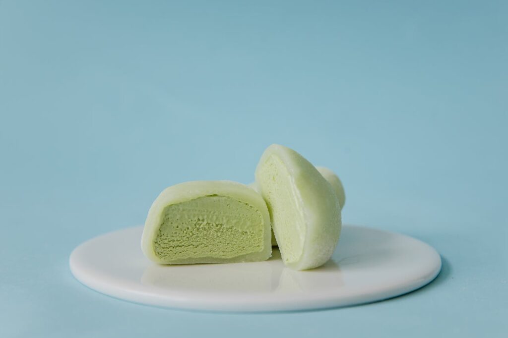 pexels-photo-8963453 Creamy green tea mochi on a white plate against a pastel blue background.
